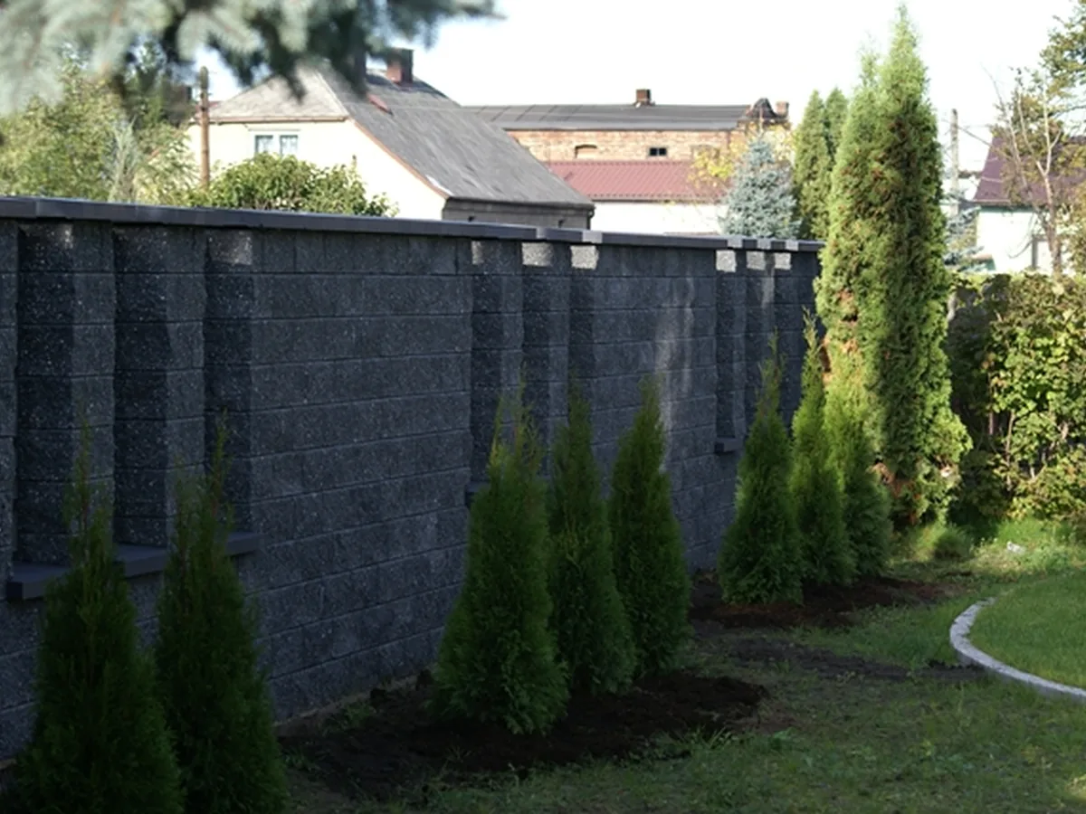 Pełne grafitowe ogrodzenie z bloczków betonowych przy ogrodzie