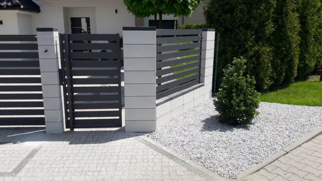 Nowoczesne grafitowe ogrodzenie z białym grysem przy podmurówce